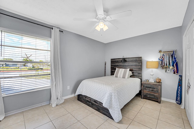 bedroom featuring light tile patterned floors, baseboards, and a ceiling fan