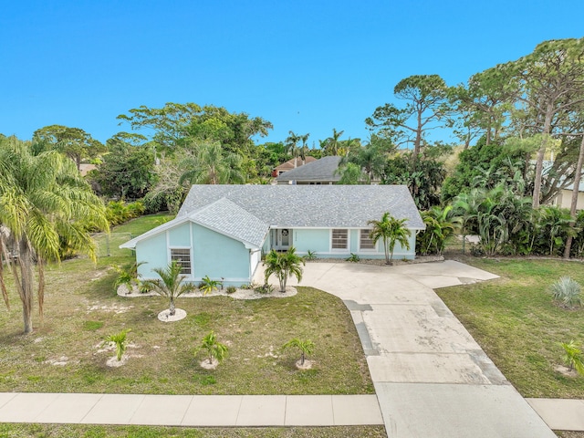 view of front facade with roof with shingles, driveway, and a front lawn