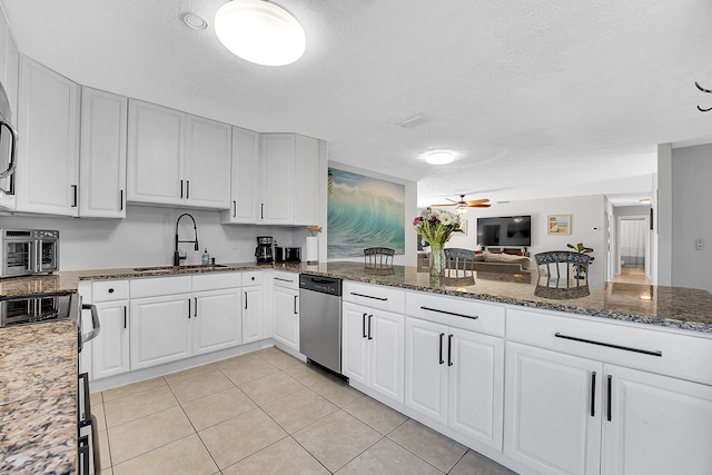 kitchen with a sink, white cabinetry, dark stone counters, and stainless steel dishwasher