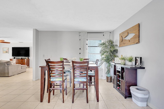 dining room with a textured ceiling, light tile patterned flooring, and baseboards