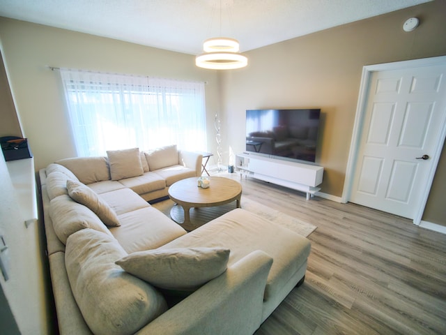 living area featuring an inviting chandelier, wood finished floors, and baseboards