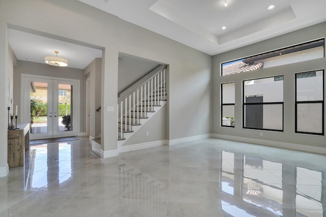 entrance foyer with french doors, stairway, a raised ceiling, and baseboards