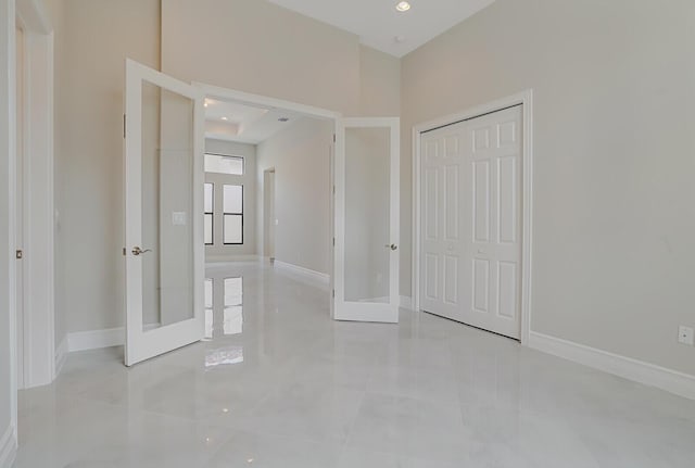 unfurnished bedroom featuring a closet, french doors, and baseboards