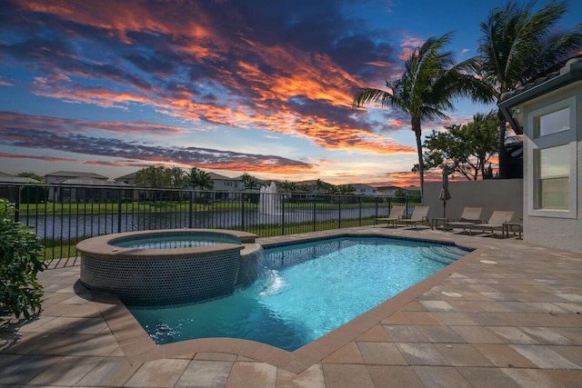 pool at dusk with a pool with connected hot tub, fence, and a patio