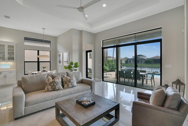 living area with recessed lighting, a ceiling fan, baseboards, visible vents, and a tray ceiling