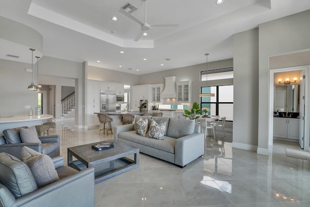 living room featuring a high ceiling, stairway, a raised ceiling, and visible vents