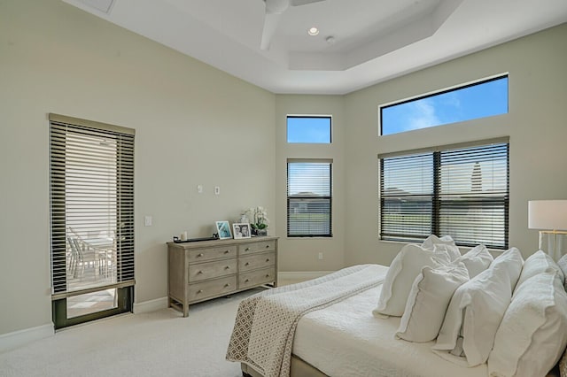 bedroom featuring baseboards, light colored carpet, access to exterior, a tray ceiling, and recessed lighting