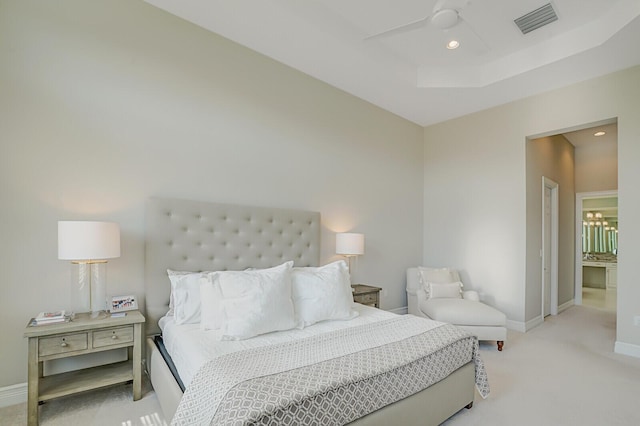 bedroom featuring light carpet, baseboards, visible vents, and a raised ceiling