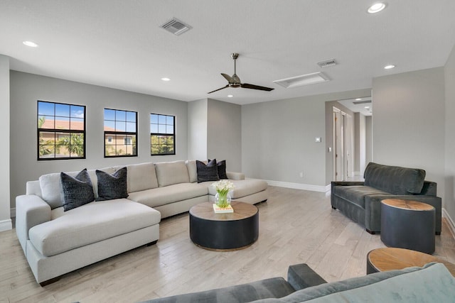 living room featuring attic access, visible vents, light wood-style flooring, and recessed lighting