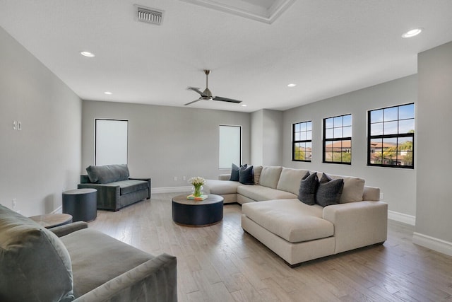 living area with light wood-style flooring, visible vents, and baseboards