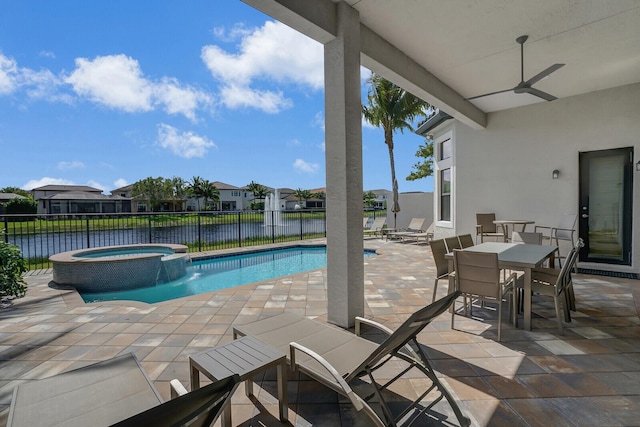 view of pool featuring fence, a pool with connected hot tub, a ceiling fan, outdoor dining space, and a patio area