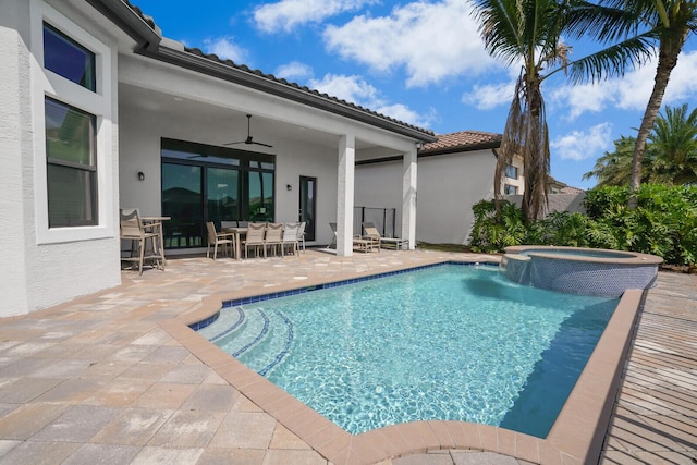 view of swimming pool featuring a pool with connected hot tub, a patio area, and a ceiling fan