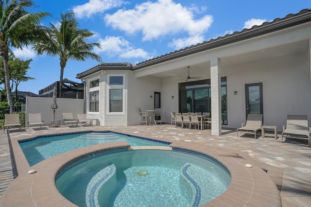 view of pool with a patio, ceiling fan, fence, outdoor dining area, and a pool with connected hot tub