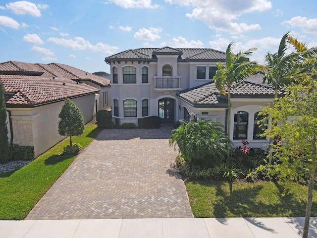 mediterranean / spanish-style home with stucco siding, decorative driveway, and a tiled roof