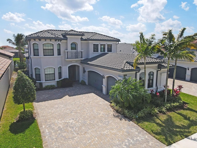 mediterranean / spanish-style house with decorative driveway, stucco siding, fence, a garage, and a tiled roof