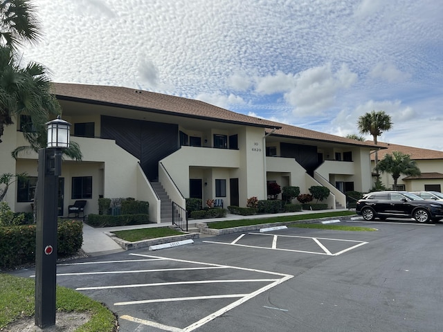 view of property with uncovered parking and stairs