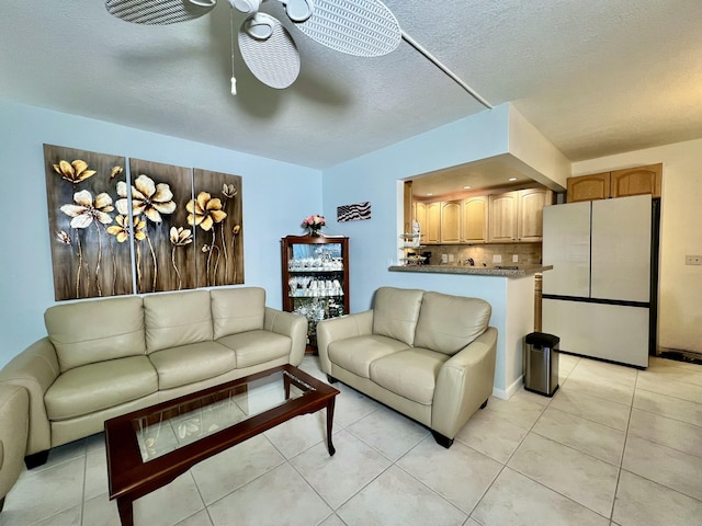 living area featuring light tile patterned floors, a textured ceiling, and ceiling fan