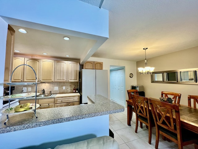 kitchen featuring tasteful backsplash, light brown cabinetry, a peninsula, freestanding refrigerator, and light tile patterned flooring