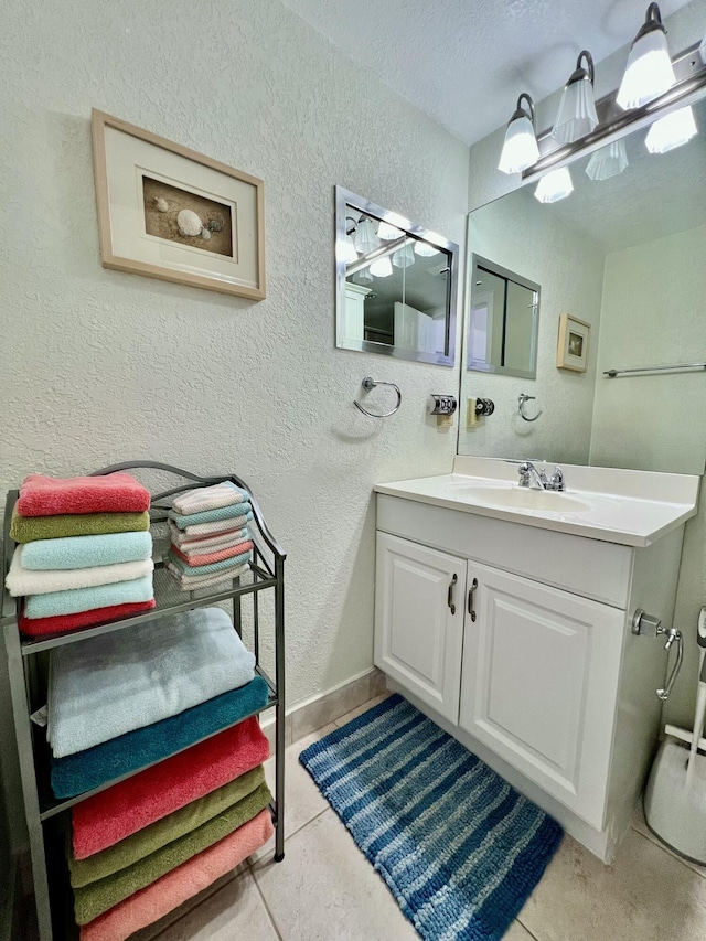 bathroom featuring a textured ceiling, vanity, baseboards, and a textured wall