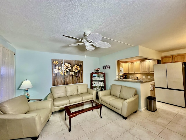 living room with light tile patterned floors, a ceiling fan, and a textured ceiling