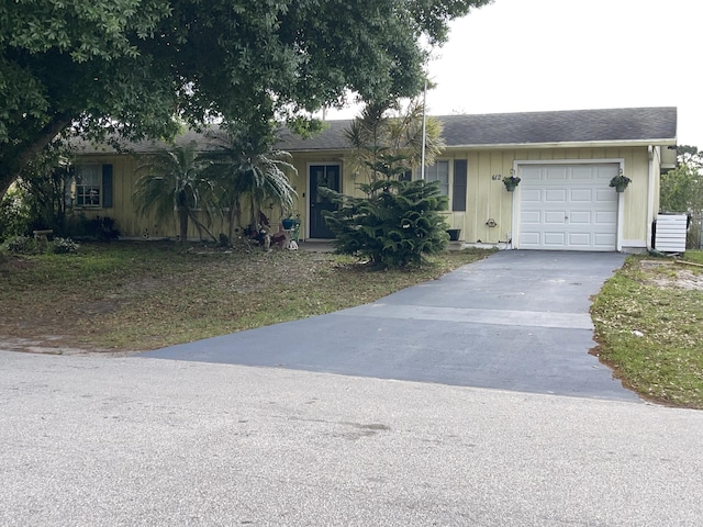 single story home featuring a garage, roof with shingles, and driveway