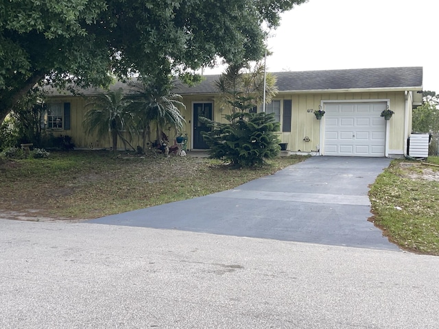 ranch-style house featuring driveway, an attached garage, and central air condition unit