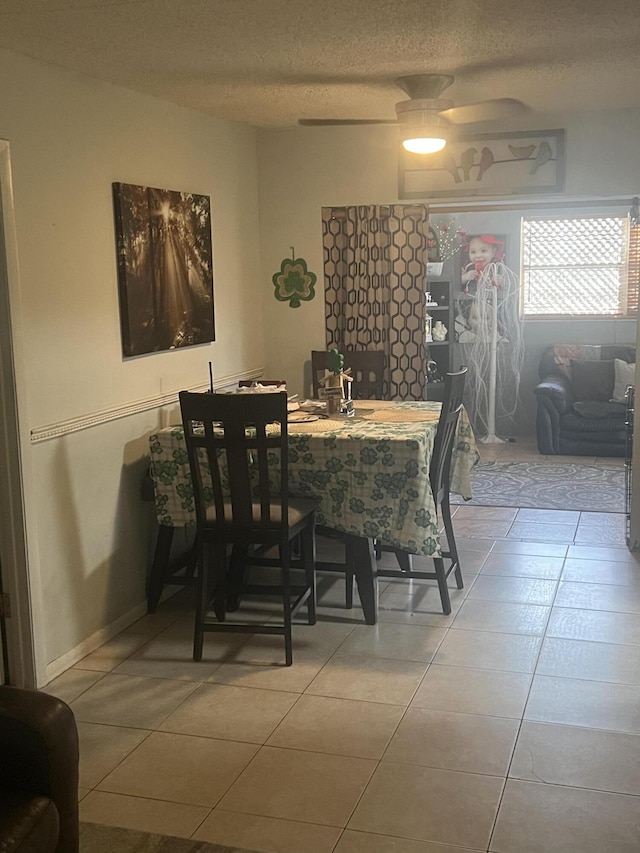 dining area featuring a textured ceiling, light tile patterned floors, and a ceiling fan