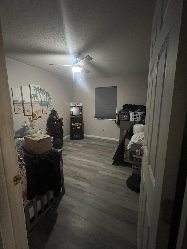 bedroom featuring a textured ceiling, ceiling fan, wood finished floors, and baseboards