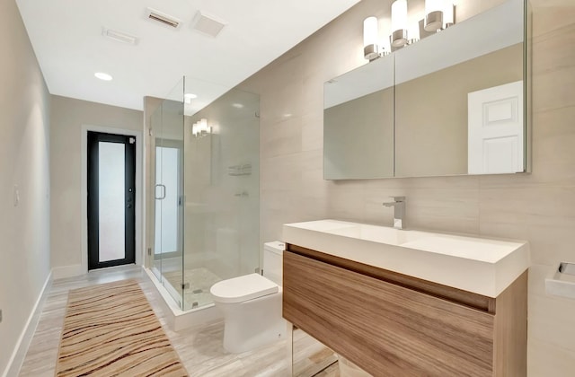 bathroom featuring toilet, visible vents, vanity, tile walls, and a shower stall