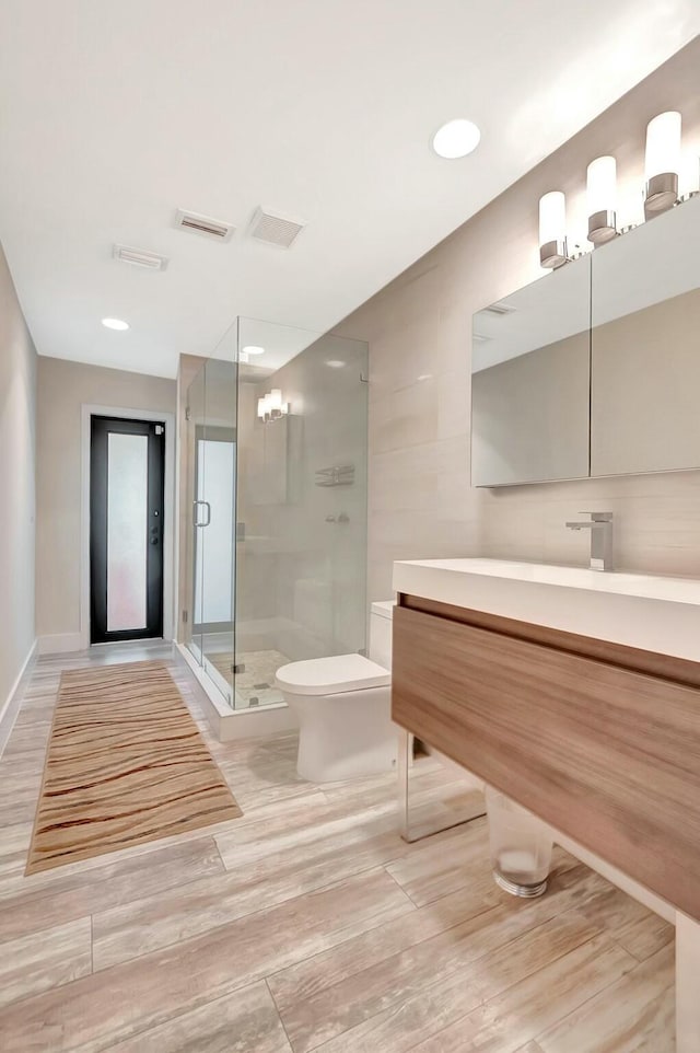 full bath featuring toilet, wood finished floors, visible vents, vanity, and a stall shower