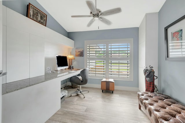 office with baseboards, ceiling fan, vaulted ceiling, light wood-style floors, and built in desk