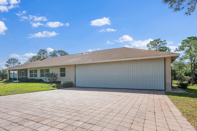 2891 SE Tailwinds Rd, Jupiter, FL 33478 - view of front of house featuring an attached garage, a front yard, stucco siding, and a chimney
