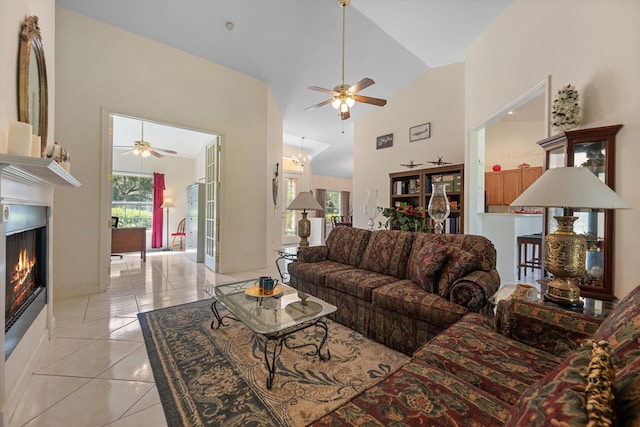 2891 SE Tailwinds Rd, Jupiter, FL 33478 - living room featuring a ceiling fan, light tile patterned flooring, high vaulted ceiling, and a lit fireplace