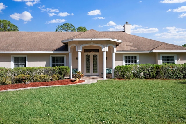 view of front of house featuring a chimney, a front yard, and stucco siding