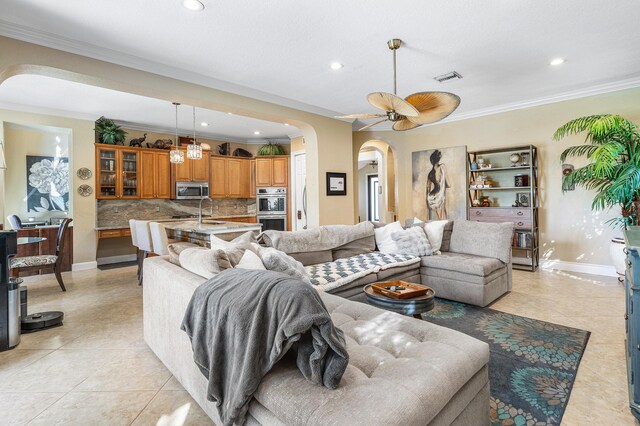 living room with arched walkways, crown molding, visible vents, light tile patterned flooring, and baseboards