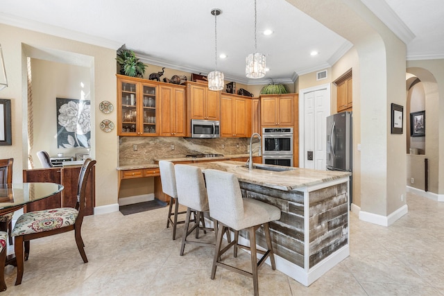 kitchen featuring visible vents, brown cabinetry, a breakfast bar area, light stone countertops, and stainless steel appliances