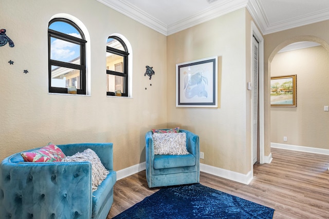 living area with baseboards, arched walkways, wood finished floors, and ornamental molding