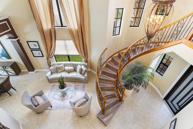 living area featuring a towering ceiling, baseboards, and stairs