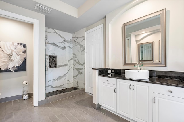 bathroom featuring baseboards, visible vents, vanity, and a marble finish shower