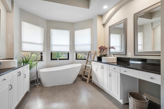 bathroom featuring recessed lighting, a freestanding tub, vanity, and wood finished floors