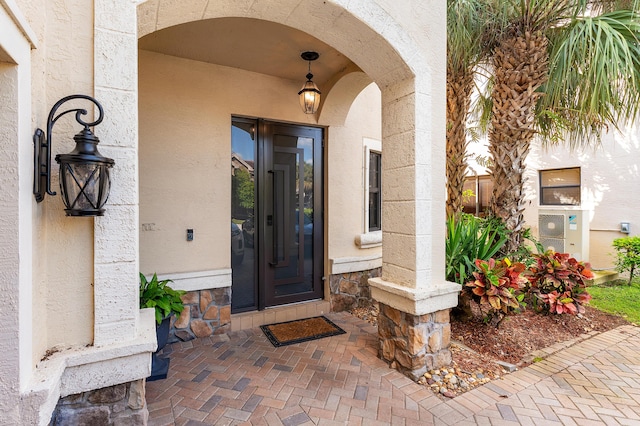 doorway to property featuring stone siding and stucco siding