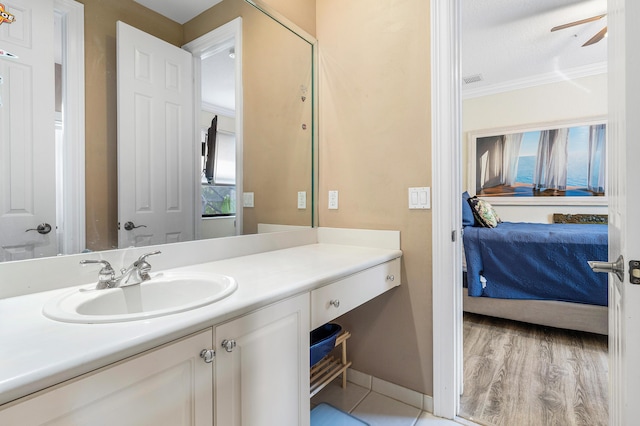 bathroom featuring baseboards, ensuite bath, wood finished floors, crown molding, and vanity