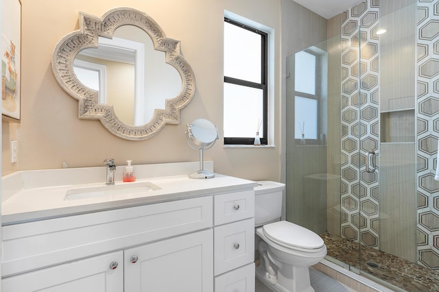 bathroom with a stall shower, vanity, and toilet