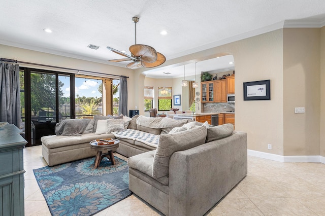 living room featuring visible vents, ornamental molding, a ceiling fan, light tile patterned flooring, and baseboards