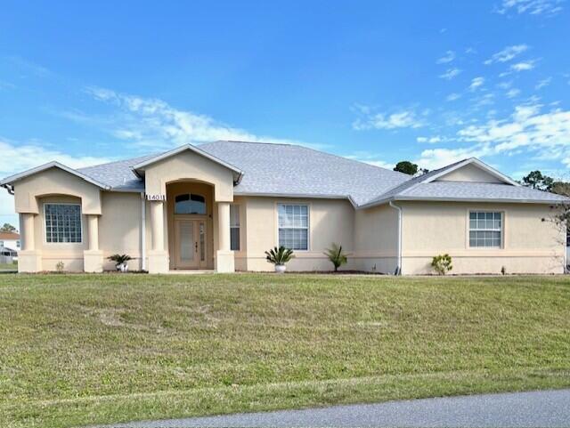 ranch-style home featuring a front lawn and stucco siding