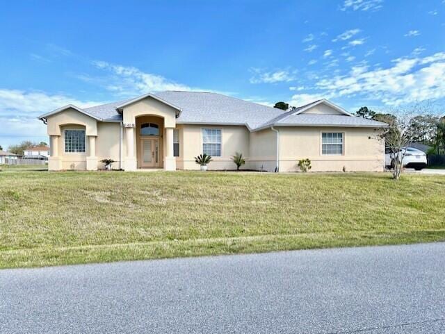 ranch-style home with a front lawn and stucco siding