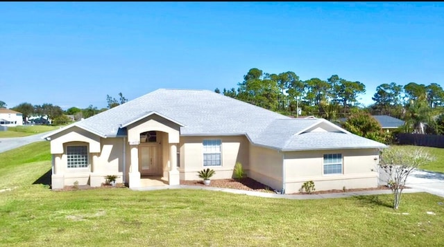 single story home with roof with shingles, a front yard, and stucco siding