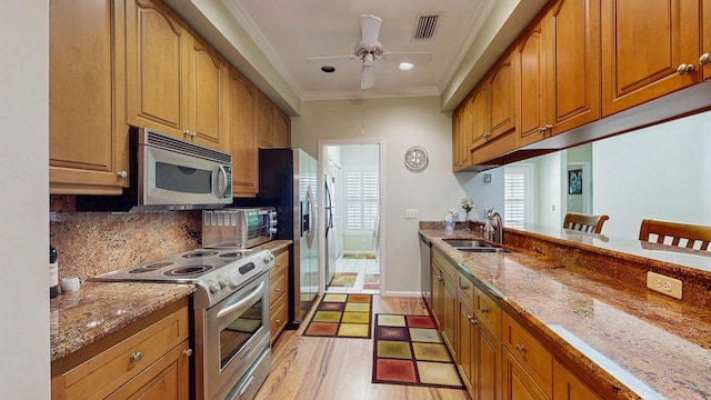 kitchen with stainless steel appliances, a sink, visible vents, a kitchen bar, and crown molding