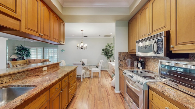 kitchen with light stone counters, decorative light fixtures, an inviting chandelier, stainless steel appliances, and crown molding