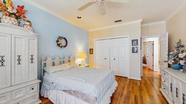 bedroom featuring dark wood-style floors, crown molding, a closet, visible vents, and baseboards